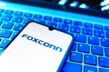 Prag, Çek Cumhuriyeti - 08 19 2025: Foxconn logosunu gösteren klavyenin üzerinde duran cep telefonunun yakından görüntüsü. Foxconn elektronik ve parça üreten bir şirket..