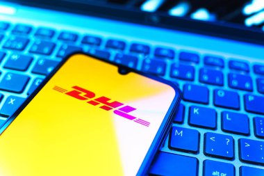 Prag, Çek Cumhuriyeti - 08 19 2025: DHL logosunu gösteren klavyenin üzerinde duran cep telefonunun yakından görüntüsü. DHL uluslararası nakliye hizmeti sunan bir lojistik şirketidir..