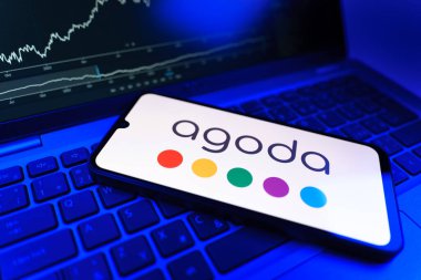 Prag, Çek Cumhuriyeti - 09 02 2025: Agoda logosunu gösteren dizüstü bilgisayarlı telefon. Agoda, otelleri ve seyahat yerlerini ayırtmak için bir platform..