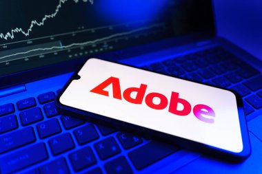 Prag, Çek Cumhuriyeti - 09 02 2025: Adobe logosunu gösteren dizüstü bilgisayarlı telefon. Adobe yaratıcı araçlar ve hizmetler sunan bir yazılım şirketidir..