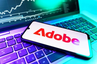 Prag, Çek Cumhuriyeti - 09 02 2025: Adobe logosunu gösteren dizüstü bilgisayarlı telefon. Adobe yaratıcı araçlar ve hizmetler sunan bir yazılım şirketidir..