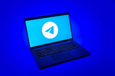 Prag, Çek Cumhuriyeti - 08 12 2025: Tek tip bir arkaplanda Telegram logosunu gösteren bir dizüstü bilgisayarın yukarıdan görünüşü. Telgraf hızlı ve güvenli iletiler için bir uygulamadır.