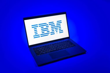 Prag, Çek Cumhuriyeti - 08 12 2025: Tek bir arkaplanda IBM logosunu gösteren bir dizüstü bilgisayarın yukarıdan aşağı görüntüsü. IBM yazılım, donanım ve danışmanlık sunan bir teknoloji şirketidir..