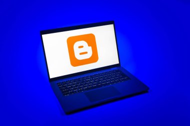 Prag, Çek Cumhuriyeti - 08 12 2025: Blog logosunu gösteren tek tip bir arkaplanda bir dizüstü bilgisayarın yukarıdan aşağı görüntüsü. Blogger blog oluşturma ve yayınlama için bir platformdur.