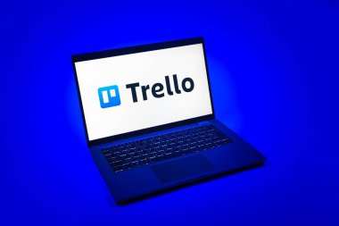 Prag, Çek Cumhuriyeti - 08 12 2025: Trello logosunu gösteren tek tip bir arkaplanda dizüstü bilgisayarın yukarıdan görünüşü. Trello, tahta ve görevleri kullanarak proje yönetimi için bir platformdur.