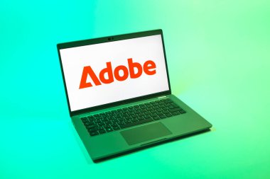 Prag, Çek Cumhuriyeti - 08 12 2025: Tek bir arkaplanda Adobe logosunu gösteren dizüstü bilgisayarın yukarıdan görünüşü. Adobe yaratıcı araçlar ve hizmetler sunan bir yazılım şirketidir..