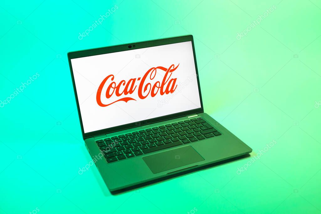 Prague, Czechia - 08 12 2025: A top-down view of a laptop on a uniform background displaying the Coca-Cola logo. Coca-Cola is a beverage company known for its soft drinks.