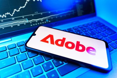 Prag, Çek Cumhuriyeti - 09 02 2025: Adobe logosunu gösteren dizüstü bilgisayarlı telefon. Adobe yaratıcı araçlar ve hizmetler sunan bir yazılım şirketidir..