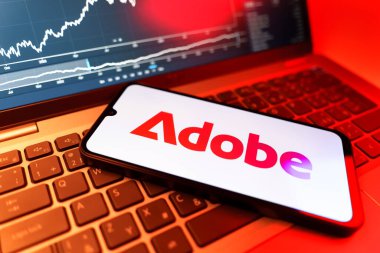 Prag, Çek Cumhuriyeti - 09 02 2025: Adobe logosunu gösteren dizüstü bilgisayarlı telefon. Adobe yaratıcı araçlar ve hizmetler sunan bir yazılım şirketidir..