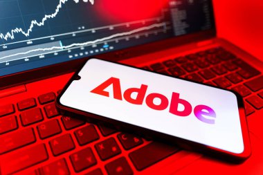 Prag, Çek Cumhuriyeti - 09 02 2025: Adobe logosunu gösteren dizüstü bilgisayarlı telefon. Adobe yaratıcı araçlar ve hizmetler sunan bir yazılım şirketidir..