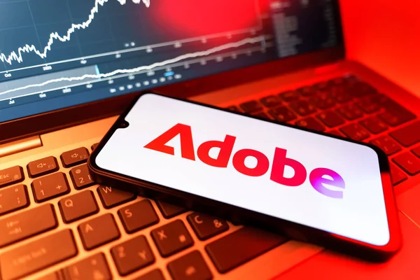 Prag, Çek Cumhuriyeti - 09 02 2025: Adobe logosunu gösteren dizüstü bilgisayarlı telefon. Adobe yaratıcı araçlar ve hizmetler sunan bir yazılım şirketidir..