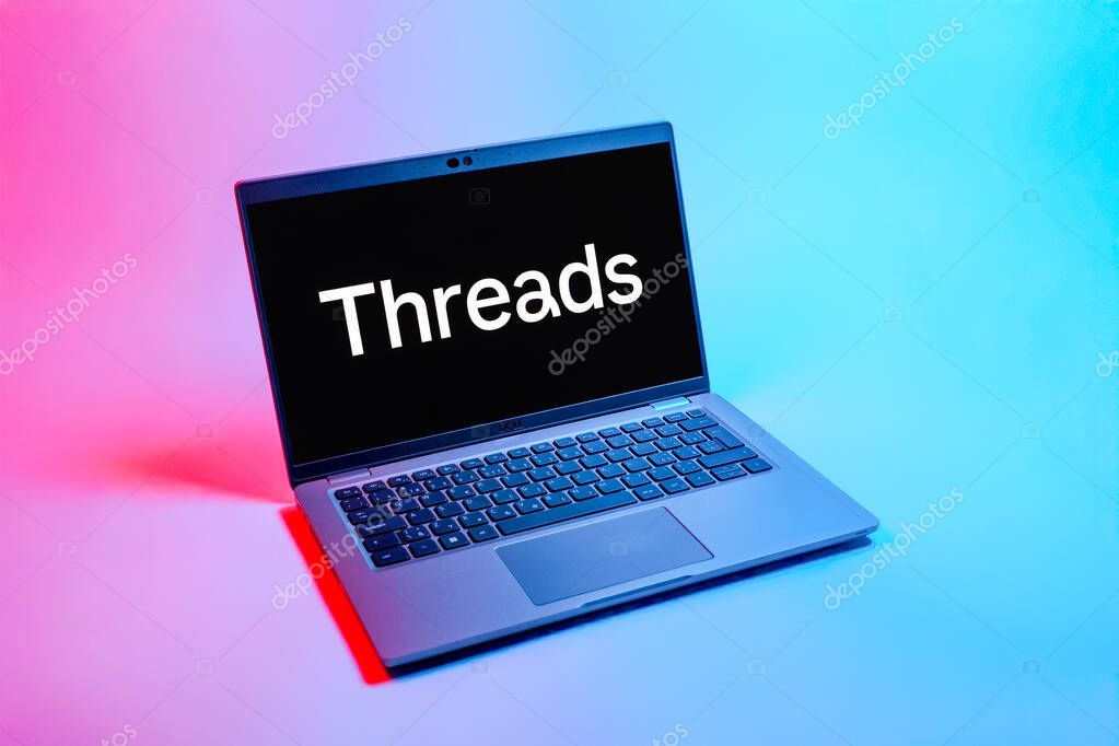 Prague, Czechia - 08 12 2025: A top-down view of a laptop on a uniform background displaying the Threads logo. Threads is a social media platform for sharing short posts and updates.