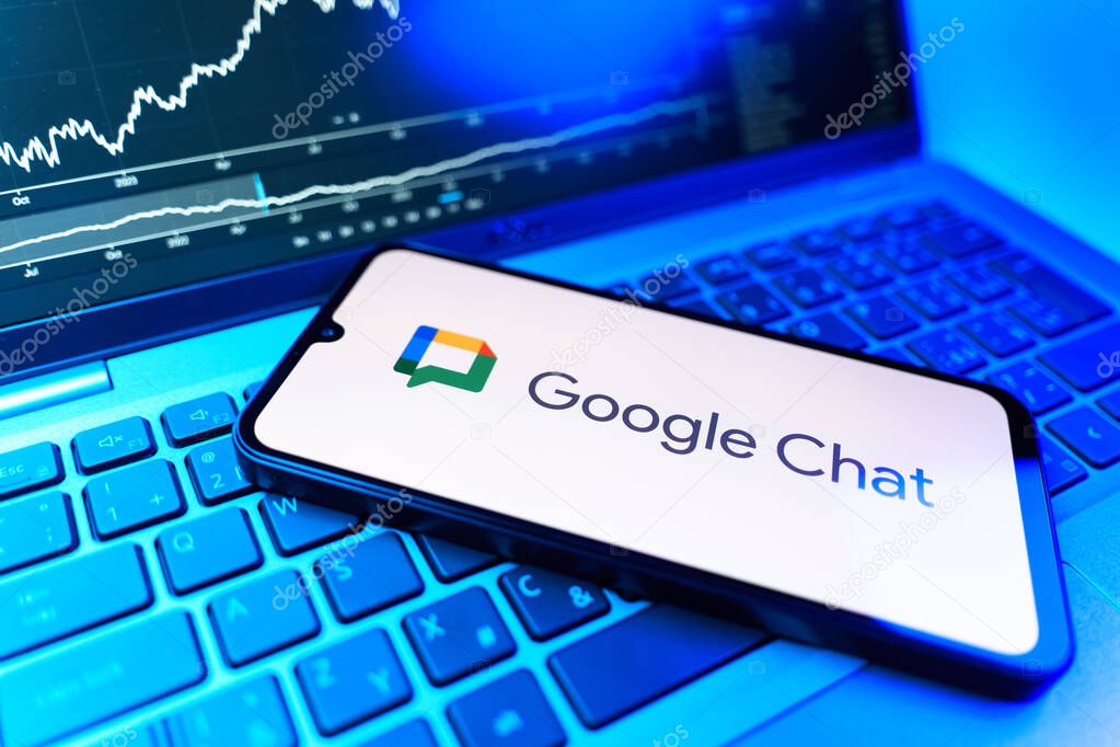 Prague, Czechia - 09 02 2025: Phone on laptop with stock chart showing Google Chat logo. Google Chat is a platform for messaging and team collaboration.