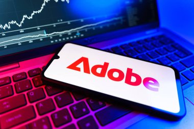 Prag, Çek Cumhuriyeti - 09 02 2025: Adobe logosunu gösteren dizüstü bilgisayarlı telefon. Adobe yaratıcı araçlar ve hizmetler sunan bir yazılım şirketidir..