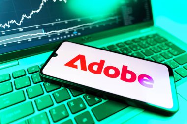 Prag, Çek Cumhuriyeti - 09 02 2025: Adobe logosunu gösteren dizüstü bilgisayarlı telefon. Adobe yaratıcı araçlar ve hizmetler sunan bir yazılım şirketidir..