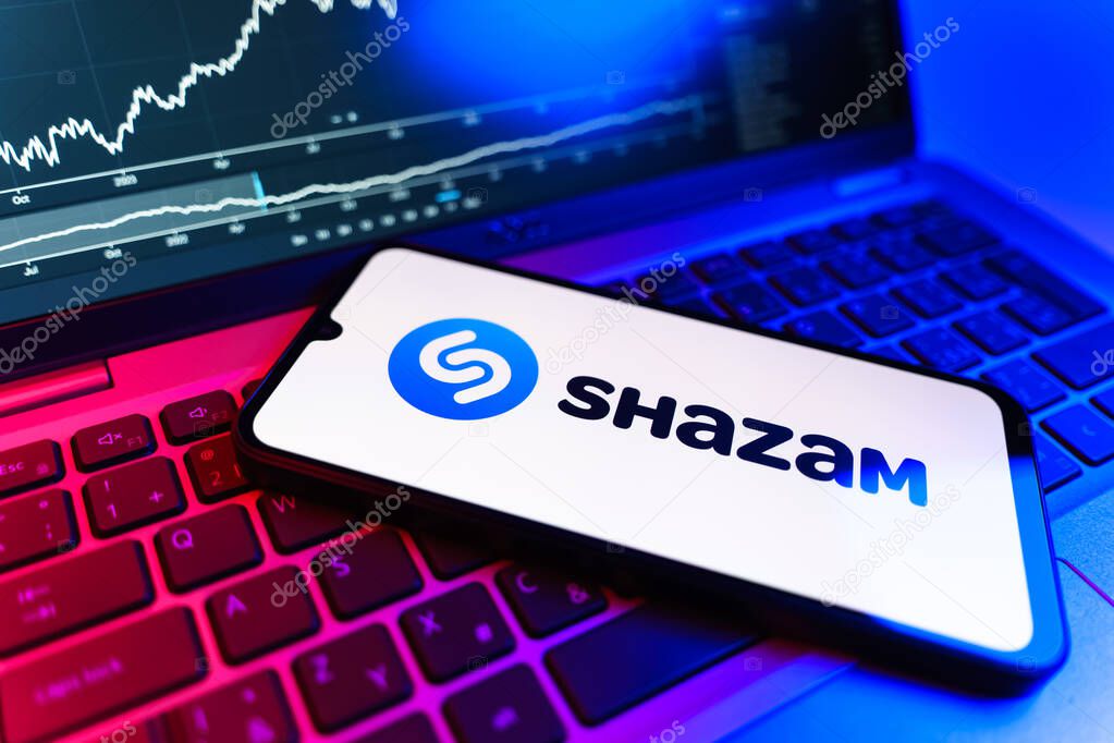 Prague, Czechia - 09 02 2025: Phone on laptop with stock chart showing Shazam logo. Shazam is an app for identifying songs and music tracks.
