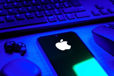 Prag, Çek Cumhuriyeti - 08 12 2025: Apple logosunu gösteren klavyesi ve cep telefonu olan bir masanın yan görüntüsü. Apple iPhone, bilgisayar ve hizmet üreten bir teknoloji şirketidir..