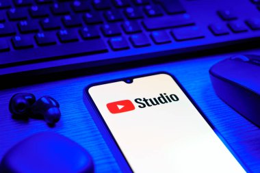 Prag, Çek Cumhuriyeti - 08 12 2025: Youtube Stüdyo logosunu gösteren klavyesi ve cep telefonu olan bir masanın yan görüntüsü. Youtube Studio YouTube kanallarını yönetmek ve analiz etmek için bir platformdur.