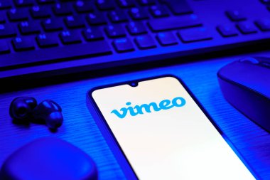 Prag, Çek Cumhuriyeti - 08 12 2025: Vimeo logosunu gösteren klavyesi ve cep telefonu olan bir masanın yan görüntüsü. Vimeo, yüksek kaliteli video sunucu ve paylaşımı için bir platformdur.