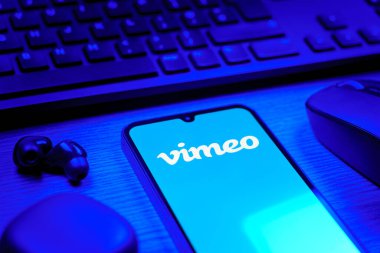 Prag, Çek Cumhuriyeti - 08 12 2025: Vimeo logosunu gösteren klavyesi ve cep telefonu olan bir masanın yan görüntüsü. Vimeo, yüksek kaliteli video sunucu ve paylaşımı için bir platformdur.