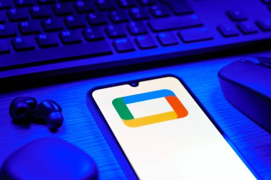 Prag, Çek Cumhuriyeti - 08 12 2025: Google TV logosunu gösteren klavyesi ve cep telefonu olan bir masanın yan görüntüsü. Google TV film, program ve uygulamalar için bir platformdur..