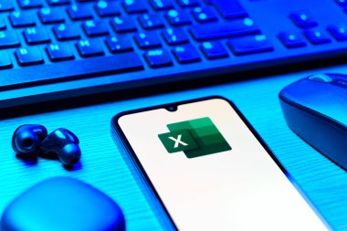 Prague, Czechia - 08 12 2025: A side view of a desk with a keyboard and a mobile phone displaying the Excel logo. Excel is a software for spreadsheets, data analysis, and calculations.