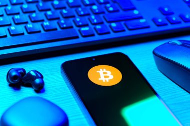 Prag, Çek Cumhuriyeti - 08 12 2025: Bitcoin logosunu gösteren klavyesi ve cep telefonu olan bir masanın yan görüntüsü. Bitcoin merkezi olmayan işlemler için dijital bir kripto para birimidir.