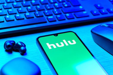 Prag, Çek Cumhuriyeti - 08 12 2025: Hulu logosunu gösteren klavyesi ve cep telefonu olan bir masanın yan görüntüsü. Hulu TV şovları, filmler ve canlı TV için bir yayın platformu..
