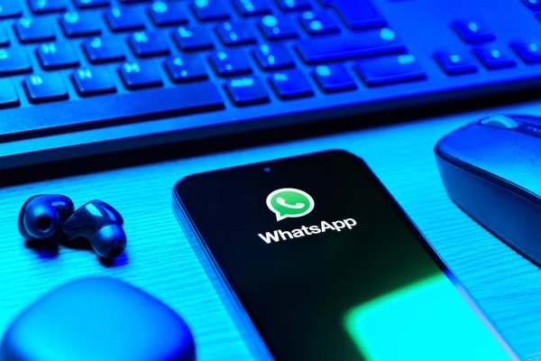 Prague, Czechia - 08 12 2025: A side view of a desk with a keyboard and a mobile phone displaying the WhatsApp logo. WhatsApp is an app for sending texts, calls, and media.