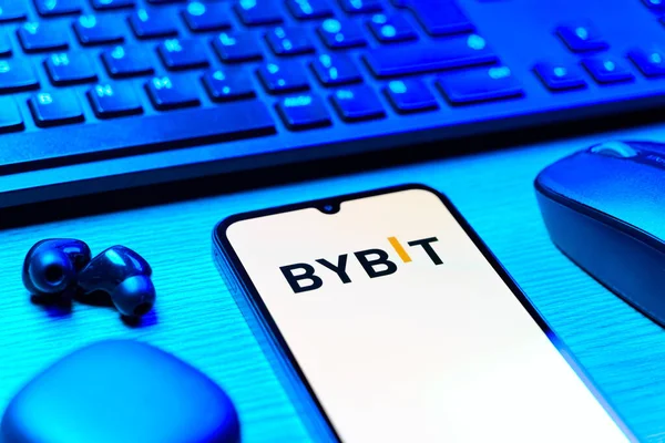 Prague, Czechia - 08 12 2025: A side view of a desk with a keyboard and a mobile phone displaying the Bybit logo. Bybit is a platform for trading cryptocurrencies and derivatives.