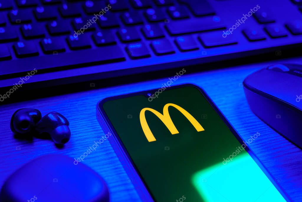 Prague, Czechia - 08 12 2025: A side view of a desk with a keyboard and a mobile phone displaying the McDonalds logo. McDonalds is a fast-food chain serving burgers, fries, and more.