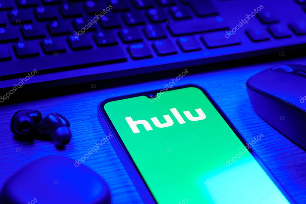 Prague, Czechia - 08 12 2025: A side view of a desk with a keyboard and a mobile phone displaying the Hulu logo. Hulu is a streaming platform for TV shows, movies, and live TV.