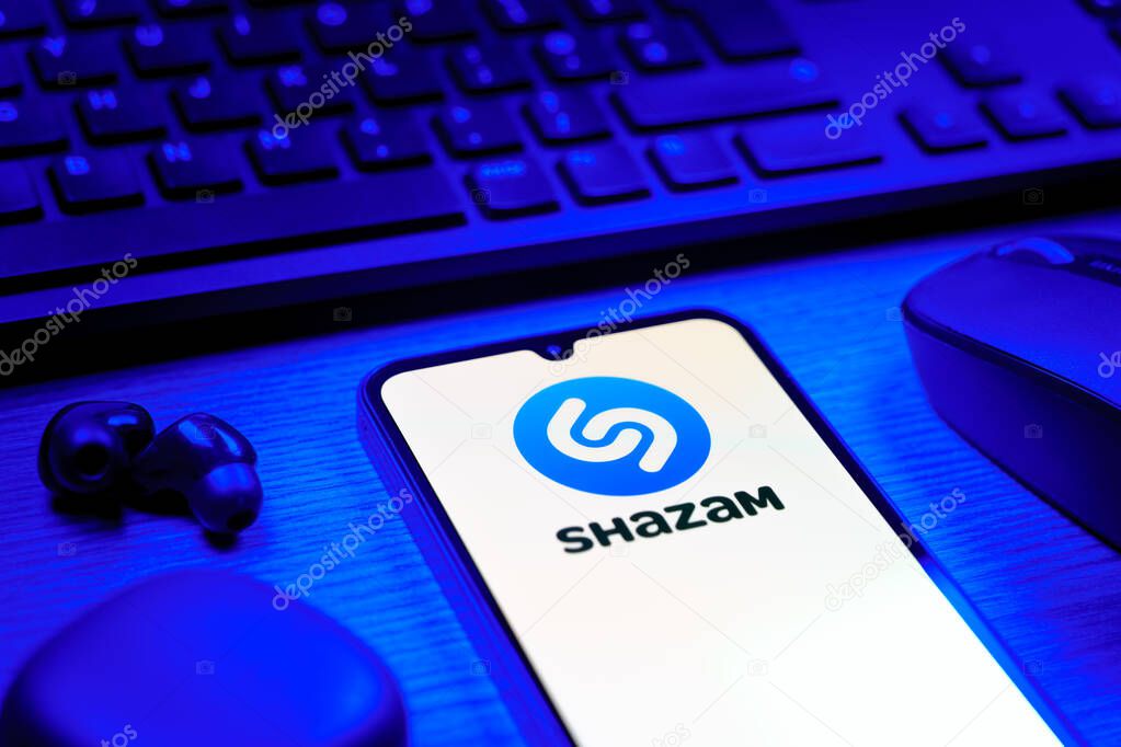 Prague, Czechia - 08 12 2025: A side view of a desk with a keyboard and a mobile phone displaying the Shazam logo. Shazam is an app for identifying songs and music tracks.