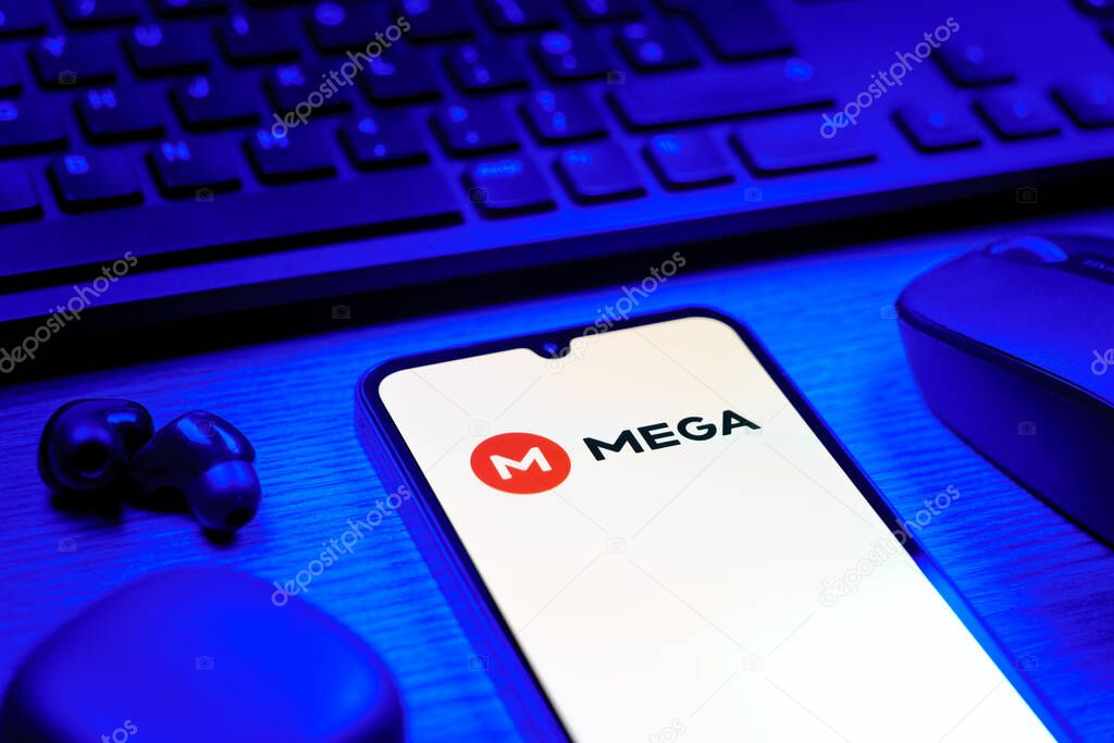 Prague, Czechia - 08 12 2025: A side view of a desk with a keyboard and a mobile phone displaying the Mega logo. Mega is a platform for cloud storage with encrypted file sharing.