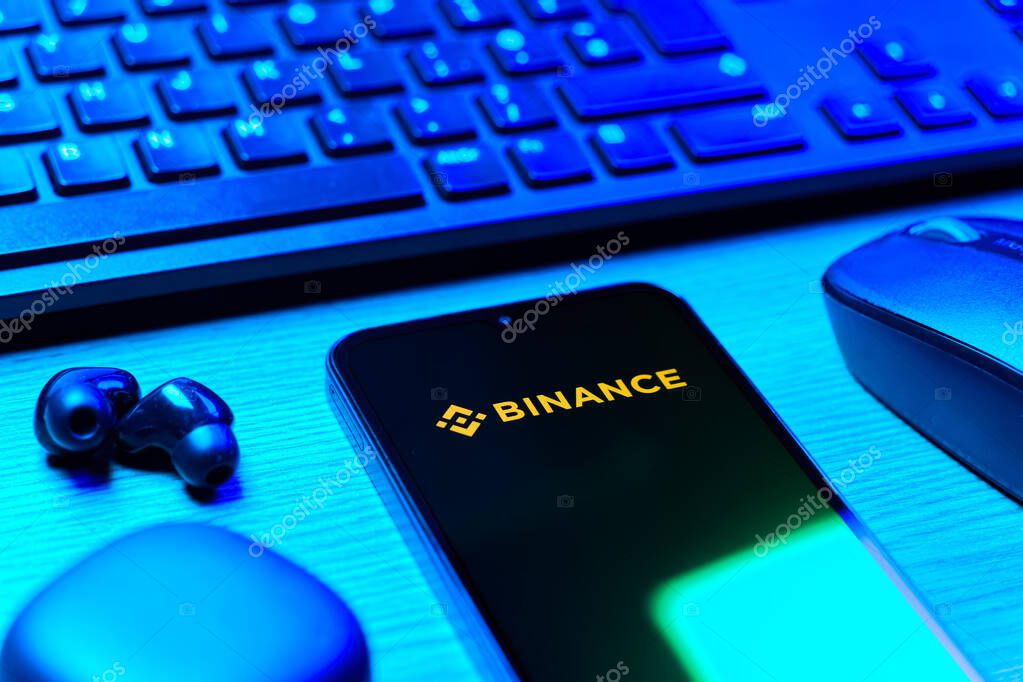 Prague, Czechia - 08 12 2025: A side view of a desk with a keyboard and a mobile phone displaying the Binance logo. Binance is a cryptocurrency exchange for trading digital assets.