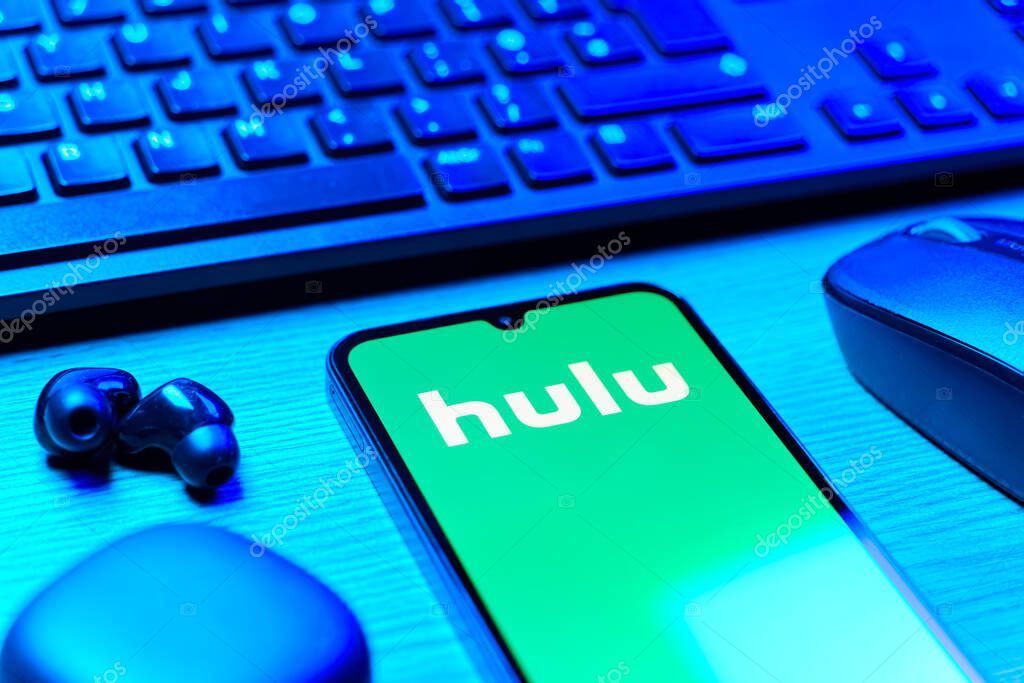 Prague, Czechia - 08 12 2025: A side view of a desk with a keyboard and a mobile phone displaying the Hulu logo. Hulu is a streaming platform for TV shows, movies, and live TV.