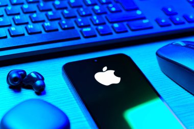 Prag, Çek Cumhuriyeti - 08 12 2025: Apple logosunu gösteren klavyesi ve cep telefonu olan bir masanın yan görüntüsü. Apple iPhone, bilgisayar ve hizmet üreten bir teknoloji şirketidir..
