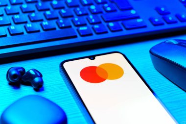 Prag, Çek Cumhuriyeti - 08 12 2025: Mastercard logosunu gösteren klavyesi ve cep telefonu olan bir masanın yan görüntüsü. Mastercard ödeme kartları ve hizmetler sağlayan bir finans şirketidir..