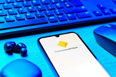 Prag, Çek Cumhuriyeti - 08 12 2025: Commonwealth Bank logosunu gösteren klavyesi ve cep telefonu olan bir masanın yan görüntüsü. Commonwealth Bank, Avustralya 'da finansal hizmetler sağlayan bir bankadır..