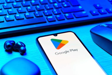 Prag, Çek Cumhuriyeti - 08 12 2025: Google Play logosunu gösteren klavyesi ve cep telefonu olan bir masanın yan görüntüsü. Google Play uygulamaları, oyunları ve dijital içeriği indirmek için bir platformdur.