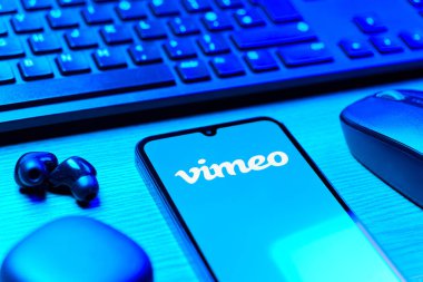 Prag, Çek Cumhuriyeti - 08 12 2025: Vimeo logosunu gösteren klavyesi ve cep telefonu olan bir masanın yan görüntüsü. Vimeo, yüksek kaliteli video sunucu ve paylaşımı için bir platformdur.