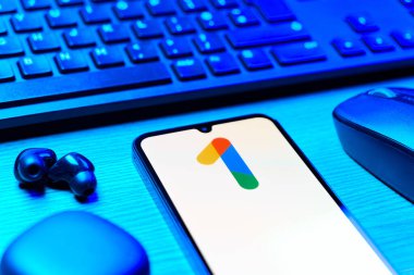Prag, Çek Cumhuriyeti - 08 12 2025: Google One logosunu gösteren klavyesi ve cep telefonu olan bir masanın yan görüntüsü. Google 1 bulut depolama ve abonelik hizmetleri için bir platformdur.