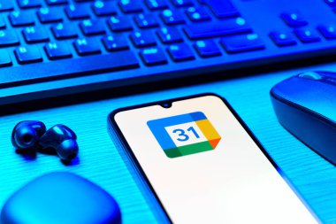 Prag, Çek Cumhuriyeti - 08 12 2025: Google Takvim logosunu gösteren klavyesi ve cep telefonu olan bir masanın yan görüntüsü. Google Takvimi olayları zamanlamak ve yönetmek için bir platformdur.