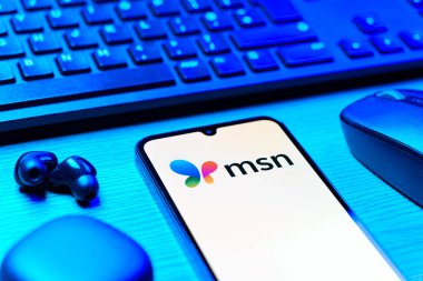 Prag, Çek Cumhuriyeti - 08 12 2025: MSN logosunu gösteren klavyesi ve cep telefonu olan bir masanın yan görüntüsü. MSN haber, e-posta ve çevrimiçi hizmetler için bir platformdur.