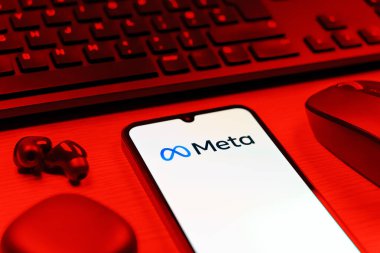 Prague, Czechia - 08 12 2025: A side view of a desk with a keyboard and a mobile phone displaying the Meta logo. Meta is a company offering social platforms like Facebook and Instagram.