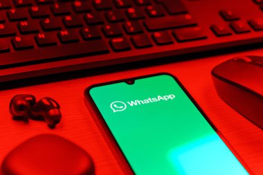 Prague, Czechia - 08 12 2025: A side view of a desk with a keyboard and a mobile phone displaying the WhatsApp logo. WhatsApp is an app for sending texts, calls, and media.