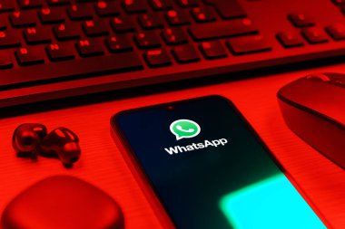 Prague, Czechia - 08 12 2025: A side view of a desk with a keyboard and a mobile phone displaying the WhatsApp logo. WhatsApp is an app for sending texts, calls, and media.