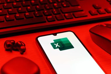 Prague, Czechia - 08 12 2025: A side view of a desk with a keyboard and a mobile phone displaying the Excel logo. Excel is a software for spreadsheets, data analysis, and calculations.