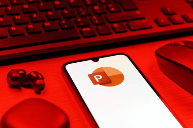 Prague, Czechia - 08 12 2025: A side view of a desk with a keyboard and a mobile phone displaying the Powerpoint logo. Powerpoint is a software for creating presentations and slideshows.