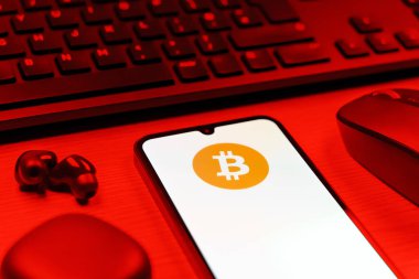 Prag, Çek Cumhuriyeti - 08 12 2025: Bitcoin logosunu gösteren klavyesi ve cep telefonu olan bir masanın yan görüntüsü. Bitcoin merkezi olmayan işlemler için dijital bir kripto para birimidir.